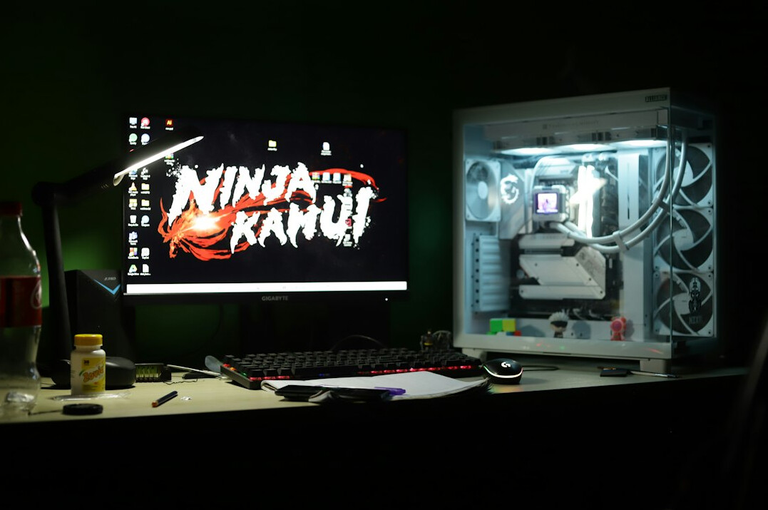 Two monitors on a desk displaying charts and code in a dim room